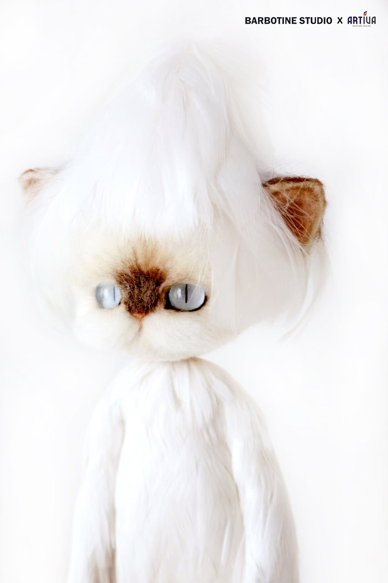 Chat tricoté en feutre de laine en tenue blanche
