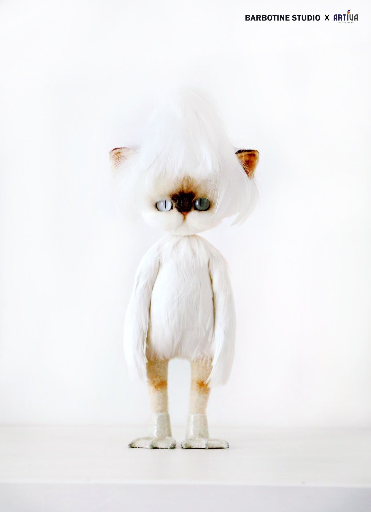Chat tricoté en feutre de laine en tenue blanche